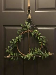 a wreath hanging on the front door with vines and leaves attached to it's sides