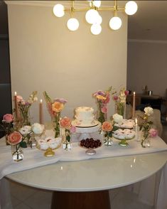 a table topped with a white cake and lots of flowers next to candles on top of it