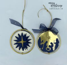 two christmas ornaments hanging from strings on a white surface with blue and gold trimmings