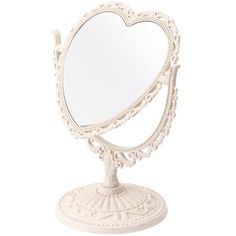 a white heart shaped mirror sitting on top of a table