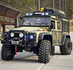 an off - road vehicle with lights on is parked in a parking lot next to a fence