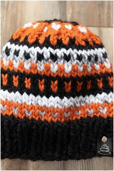 an orange and black knitted hat sitting on top of a wooden floor