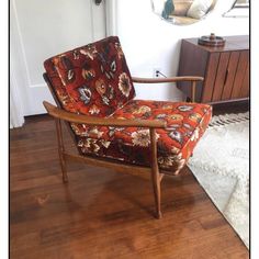 a chair sitting on top of a hard wood floor next to a mirror and rug