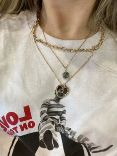 a woman wearing a white shirt with a horse on it's chest and two necklaces hanging from her neck