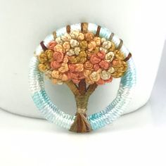 a tree made out of beads on top of a white vase with a ribbon around it