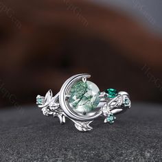 a ring with green stones and leaves on it