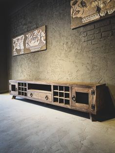 a large wooden entertainment center with two paintings on the wall