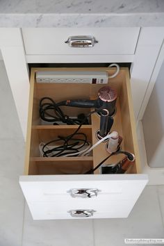 an open drawer with hair dryers and other items in it