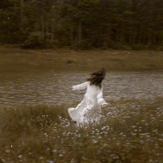 a woman in a white dress is running through the water