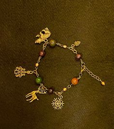 "A bracelet specially designed with the season of Yule in mind. Crystals: Garnet & Bloodstone. Charms: Bran, Pine Tree, Stag, Snowflake, Pine Cone. Other beads: Firepolish bead in gold. Please note Bloodstone naturally varies in color. Bracelet is 9in total but can be closed starting at 7 3/4in. Crystals, animals, colors and symbols correspondences researched and carefully selected using Edain McCoy's \"Sabbats. A witch's approach to living the Old Ways\" and Llewellyn's Sabbat Essentials Collection. Stones, beads and charms cleansed with Sabbat appropriate incense.  Jewelry items are placed in a reusable muslin bag with beautifully scented dried lavender from my own garden, and lots of good vibes. Fill your muslin bag with additional herbs to toss in your bathtub for a beautifully scented Handmade Metal Crystal Bracelet As A Gift, Metal Beaded Charm Bracelet Gift, Handmade Christmas Jewelry Bracelets, Handmade Christmas Bracelet Jewelry, Handmade Christmas Bracelet, Handmade Holiday Bracelet Jewelry, Handmade Gold Bracelets For Holiday, Adjustable Costume Jewelry Charm Bracelet As Gift, Metal Crystal Bracelet Costume Jewelry Gift