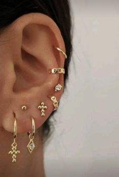 a woman wearing ear piercings with cross and diamond designs on the side of her ear