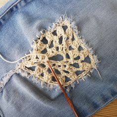 a pair of jeans with crochet on them and a knitting needle in the pocket