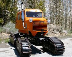 an orange tractor is parked on the side of the road in front of some trees