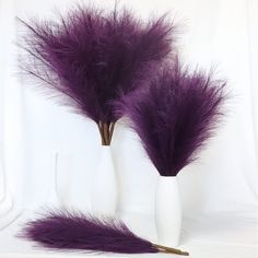 two white vases with purple feathers in them