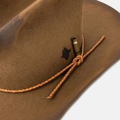 Designed in collaboration with bespoke hat-makers Coup de Tete, this classic cowboy hat is as handcrafted as they come. Flame-distressed texture and scorched hot-knife detailing complement the bullet hole that pierces through the hat's brim and crown. A bullet casing sits beside our monogram, which has been branded into the fur felt exterior. The woven leather detailing and co-branded leather inner band serve as the finishing touches on a hat that is designed to last a lifetime. Small: 7 1/4 (58 Rugged Brimmed Hat Bands For Ranch, Rugged Hats With Curved Brim For Western-themed Events, Rugged Distressed Brown Hat Bands For Rodeo, Rugged Short Brim Hat For Western-themed Events, Rugged Flat Brim Fedora For Ranch, Rustic Distressed Brown Hat Band For Ranch, Rugged Brimmed Fedora For Western-themed Events, Rugged Fedora With Short Brim For Western-themed Events, Rugged Fedora With Flat Brim For Western-themed Events