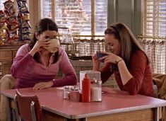 two women sitting at a table drinking coffee