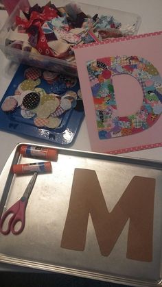 the letter m is made out of fabric and paper with scissors next to it, along with other crafting supplies