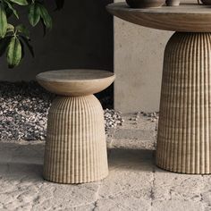 two vases sitting next to each other on top of a cement slab near a potted plant