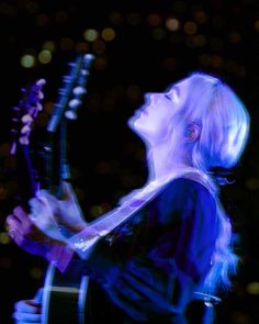 a woman with blonde hair playing an electric guitar