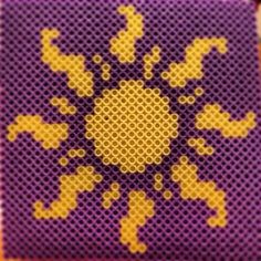 a close up of a purple and yellow cross stitch pattern on a piece of cloth