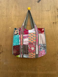 a multicolored patchwork bag hanging on a wooden wall