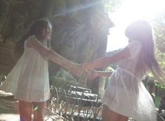 two girls in white dresses holding hands