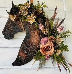 a horse mask with flowers and foliage on the side of a door, next to a wall