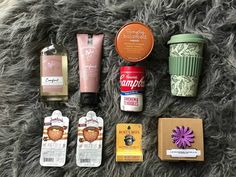 the contents of an assortment of beauty products laid out on a furry surface, including soaps, hand sanitizers and coffee cups