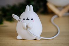 a little white bunny holding a charger plugged in