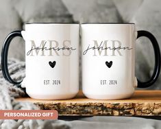 two personalized coffee mugs sitting on top of a wooden table next to a blanket