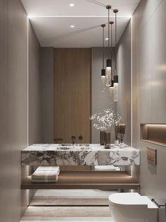 an elegant bathroom with marble counter tops and gold accents, along with modern lighting fixtures