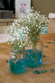 two mason jars filled with water and baby's breath are sitting on a table