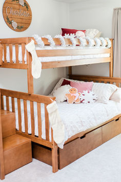 a bunk bed with two sets of drawers underneath it and a wooden sign on the wall