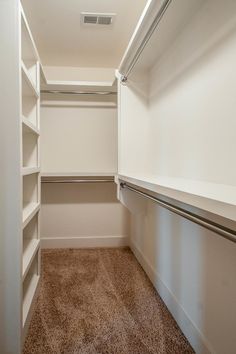 an empty walk in closet with carpeted flooring and white shelving unit doors