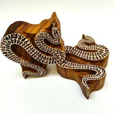 an intricate wooden brooch sits on top of a piece of wood and is decorated with black and white designs