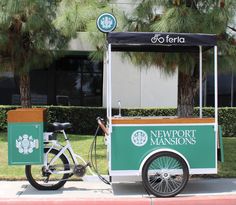 a bike parked next to a green and white food cart on the side of a road