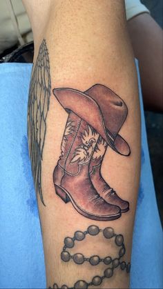 a tattoo on the arm of a man with a cowboy boot and angel wings