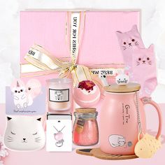 a pink gift box with various items on it and a cat figurine next to it