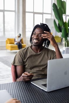 a man sitting at a table with a laptop and cell phone in front of him