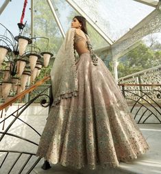 a woman in a wedding dress standing on stairs with her back turned to the camera