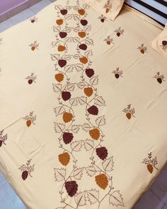 a bed covered in a white sheet with brown and orange flowers on the coverlet