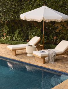 two lounge chairs and an umbrella next to a swimming pool