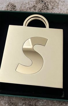 the letter s is on top of a black and white box with a gold handle