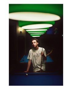 a man standing in front of a pool table with a cue stick and ball on it