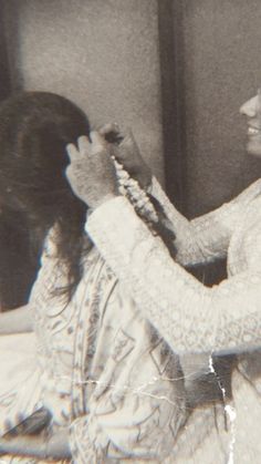 an old black and white photo of two women in front of a mirror brushing their hair