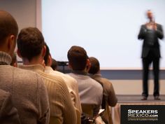 a man standing in front of a group of people while giving a presentation on a projector screen