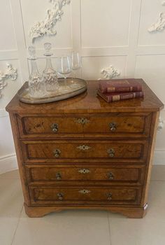 an old wooden dresser with books and glasses on top