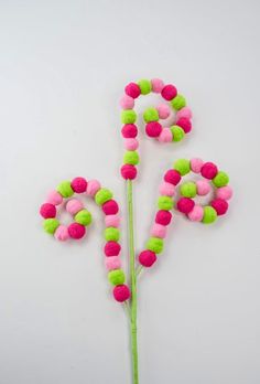 two pink and green pom - poms in the shape of letters on a white surface