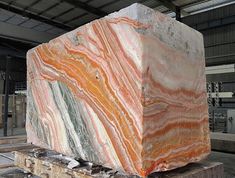 an orange and white marble block sitting on top of a wooden pallet in a warehouse