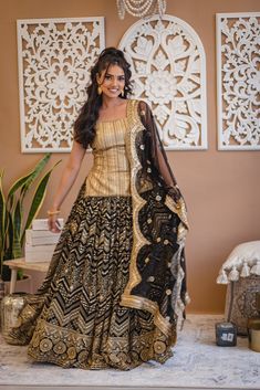 Loyla - Black Georgette Lengha & Gold Silk Choli w/ Mirror & Bead Embroidery If elegance had to be visually depicted then this black and gold lehenga choli would speak volumes with its sophistication! Gold dupion silk choli w/ sequins & bead handwork Breathable golden Dupion silk blouse Graceful scoop neckling choli blouse Beaded trim detail at neck & hemline Gorgeous sequin & bead embroidery Sweetheart back neck with tie-up Dori Flowy black georgette lehenga w/ mirror embroi Traditional Palazzo Set With Gold Embroidery For Reception, Bollywood Style Raw Silk Palazzo Set With Gold Embroidery, Bollywood Palazzo Set With Gold Embroidery For Festivals, Black Chanderi Palazzo Set With Mirror Work, Bollywood Palazzo Set With Gold Embroidery For Diwali, Black Resham Embroidered Palazzo Set For Reception, Black Palazzo Set For Reception During Eid, Black Palazzo Set For Eid Reception, Black Anarkali Sharara With Cutdana